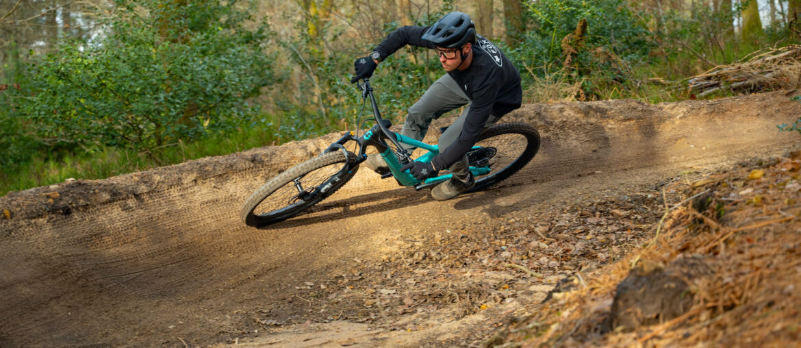 A rider on a Scott Full-Suspension mountain bike rides around a bermed corner