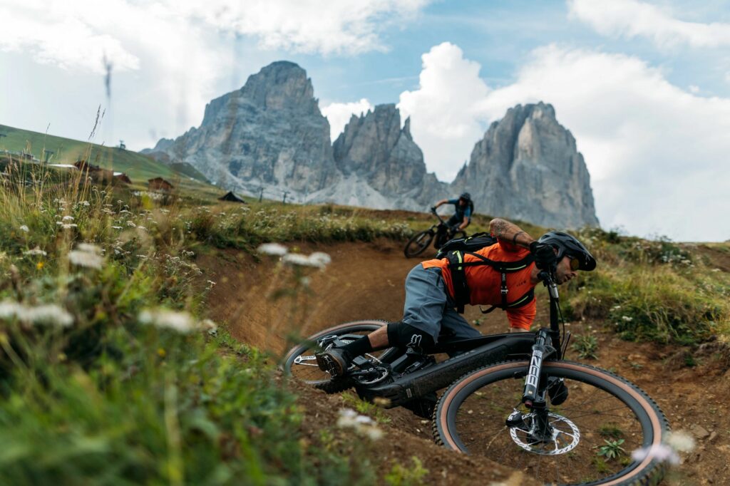 2 Riders on Trek Rail+ Electric Mountain bikes ride around a banked corner on a trail in the dolomites