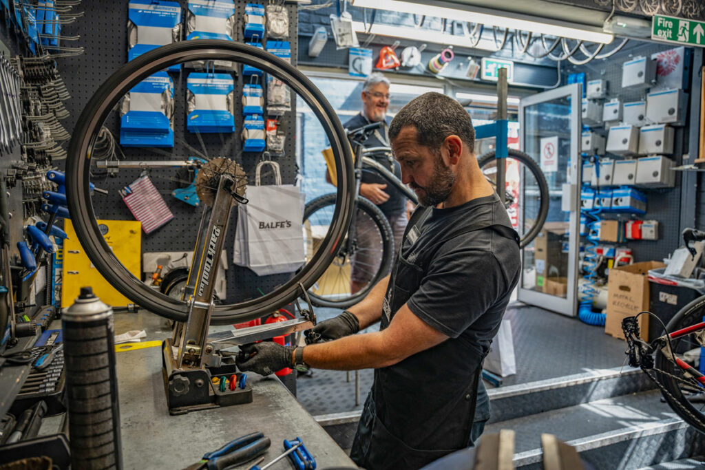 mechanic working on a wheel in a wheelstand in a balfe's bikes workshop