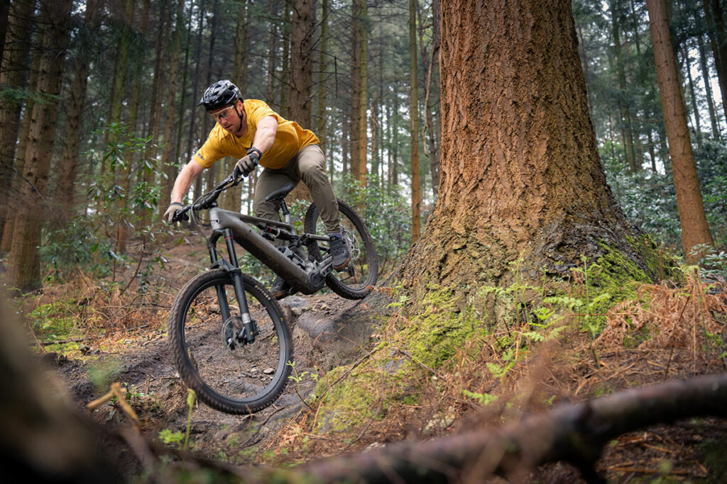 A mountain bike rider riding over a steep rooty section wearing a Fox Speedframe pro MTB helmet