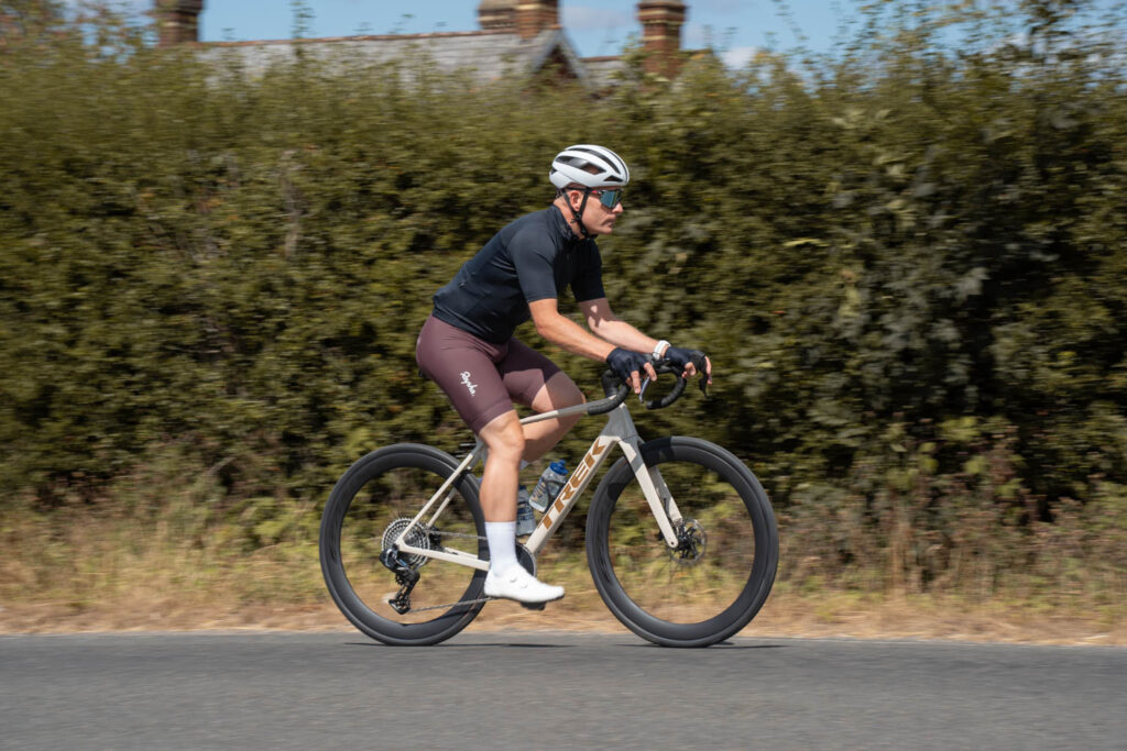 Wide shot of cyclist riding Trek Domane Gen 5 on countryside road